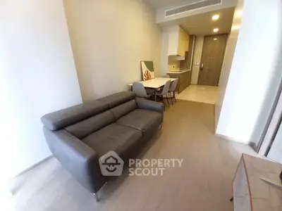 Modern living room with sleek leather sofa and open kitchen layout in a stylish apartment.