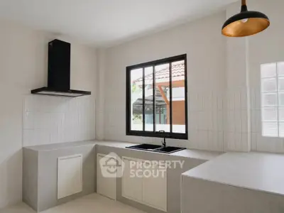 Modern kitchen with sleek design, featuring large window and stylish lighting, perfect for culinary enthusiasts.