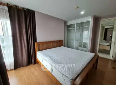 Spacious bedroom with wooden bed frame and ensuite bathroom in modern apartment.