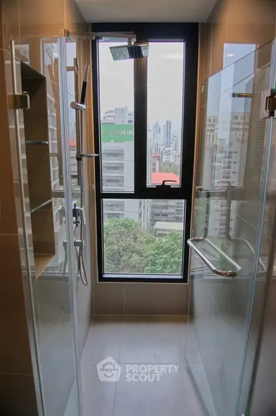 Modern bathroom with glass shower and city view from window.