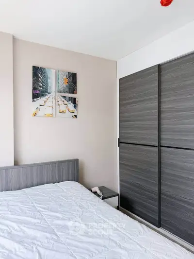Modern bedroom with sleek gray wardrobe and stylish cityscape artwork.