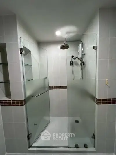 Modern bathroom with glass shower enclosure and sleek tile design.