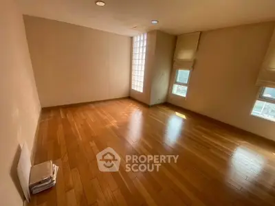 Spacious empty room with wooden flooring and natural light, ideal for customization.