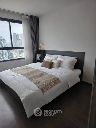 Modern bedroom with city view, featuring a cozy bed and elegant decor in a high-rise apartment.