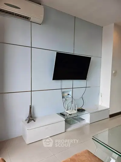 Modern living room with wall-mounted TV and sleek white cabinets