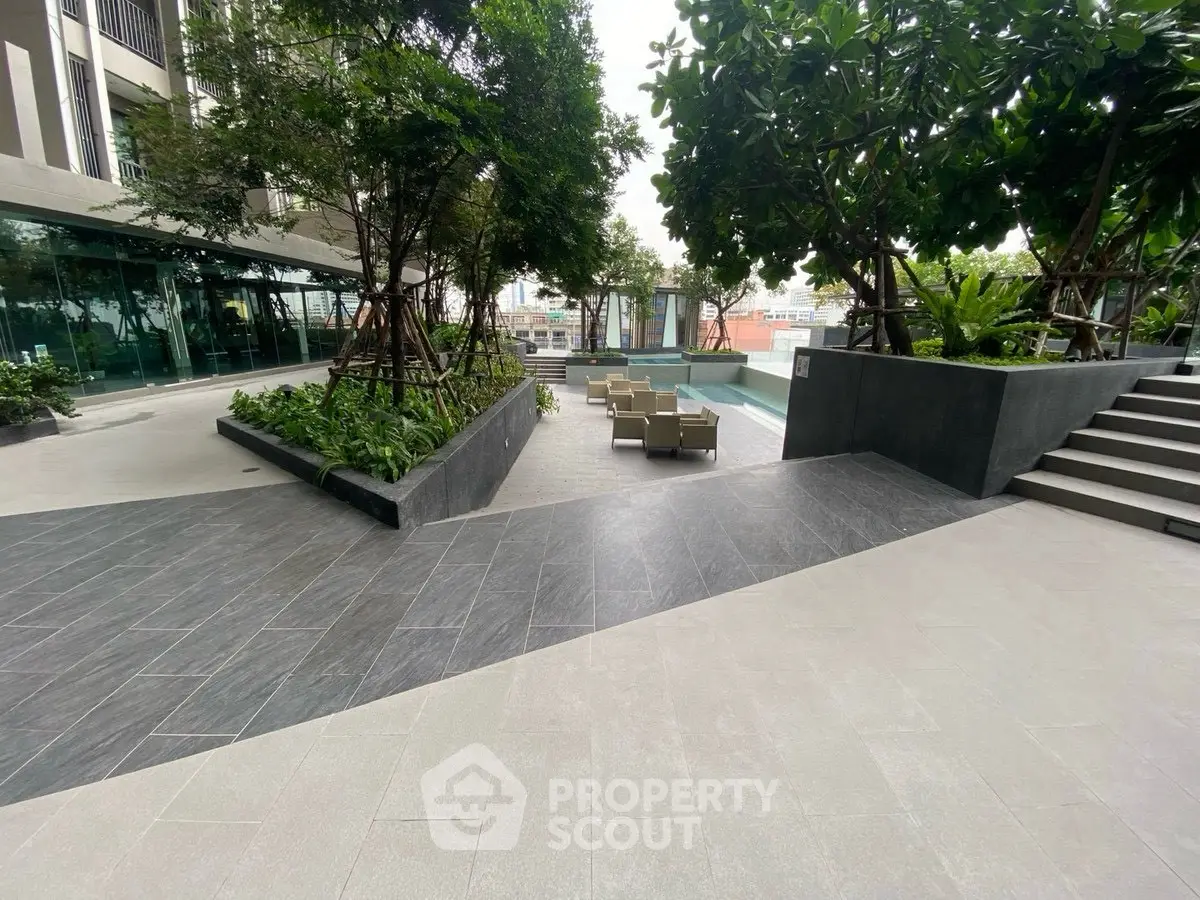 Modern outdoor pool area with stylish seating and lush greenery in a luxury apartment complex.