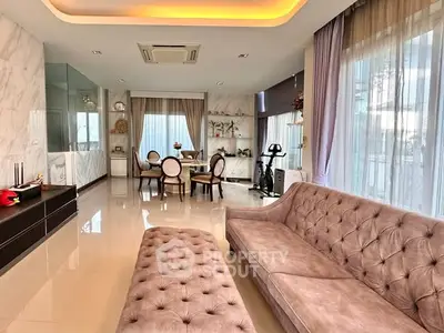 Luxurious living room with elegant furniture and exercise equipment, featuring large windows and modern decor.