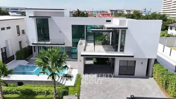 Luxurious modern villa with pool and spacious driveway, featuring sleek architectural design and lush greenery.