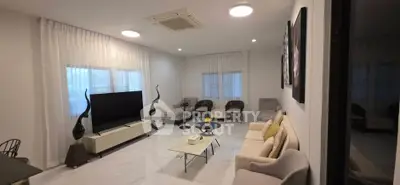 Spacious modern living room with elegant decor and large TV, perfect for relaxation and entertainment.