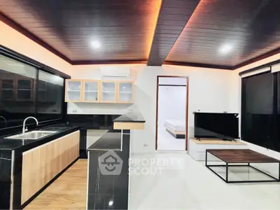 Modern open-layout kitchen and living room with sleek black and wood finishes, featuring a cozy ambiance.