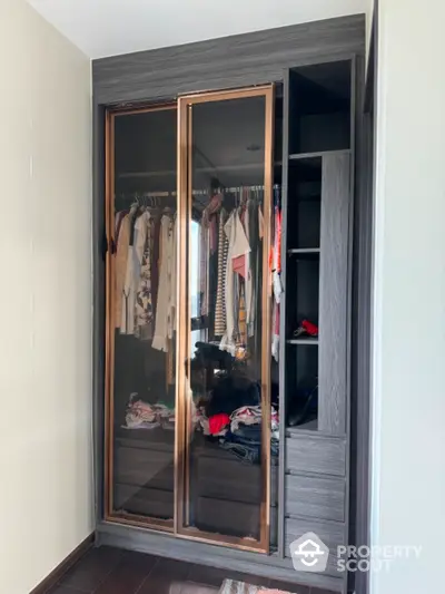 Modern wardrobe with sliding glass doors and organized clothing storage