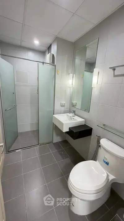 Modern bathroom with glass shower and sleek fixtures in contemporary apartment.