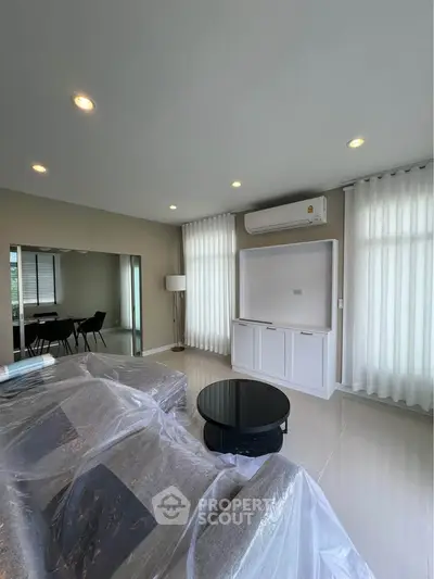 Modern living room with sleek furniture and natural light, featuring air conditioning and elegant decor.