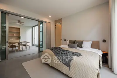Modern bedroom with sliding doors opening to a stylish dining area, featuring elegant decor and natural light.