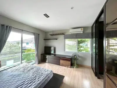Spacious bedroom with large windows and modern furnishings, featuring a serene view.