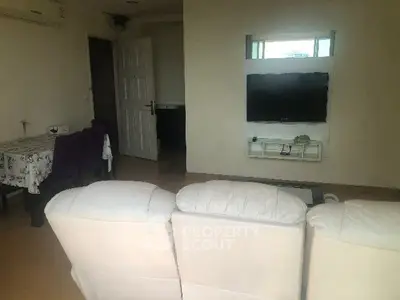 Cozy living room with white sofa and wall-mounted TV, perfect for relaxation.