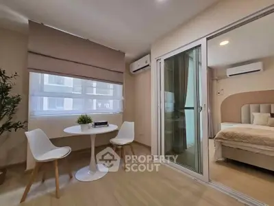 Modern bedroom with sliding glass door and cozy dining area, featuring elegant decor and natural light.