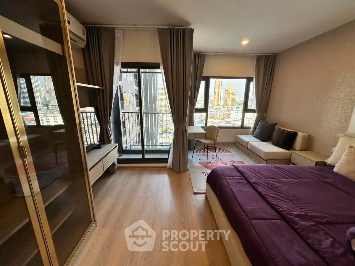 Modern bedroom with city view, featuring a cozy bed, stylish decor, and a small balcony overlooking skyscrapers.