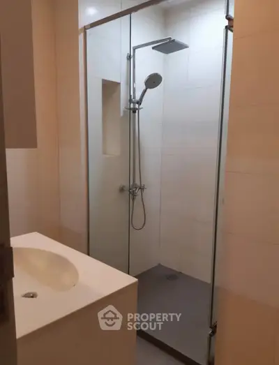 Modern bathroom with glass shower enclosure and sleek sink design.
