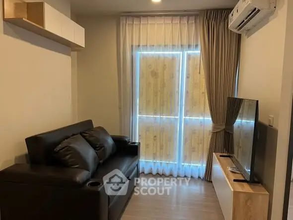 Cozy living room with modern sofa and flat-screen TV, perfect for relaxation.