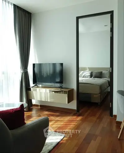 Modern living room with sleek TV stand and view into cozy bedroom