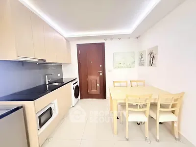 Modern kitchen with dining area, featuring light wood cabinets and integrated appliances.