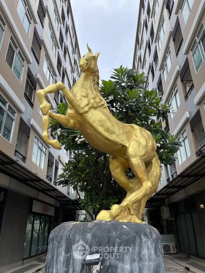 Stunning golden horse statue in modern urban courtyard, surrounded by contemporary architecture.