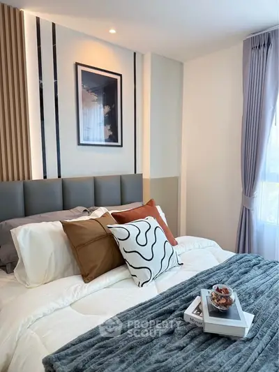 Cozy bedroom with modern decor, plush bedding, and natural light from large window.