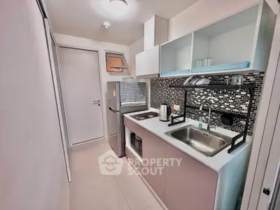 Modern compact kitchen with sleek design and mosaic backsplash in urban apartment.