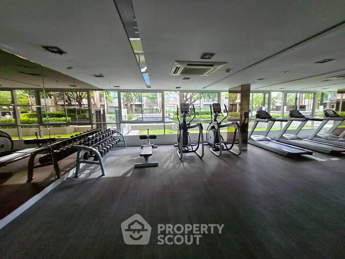 Spacious gym with modern equipment and large windows offering garden views.
