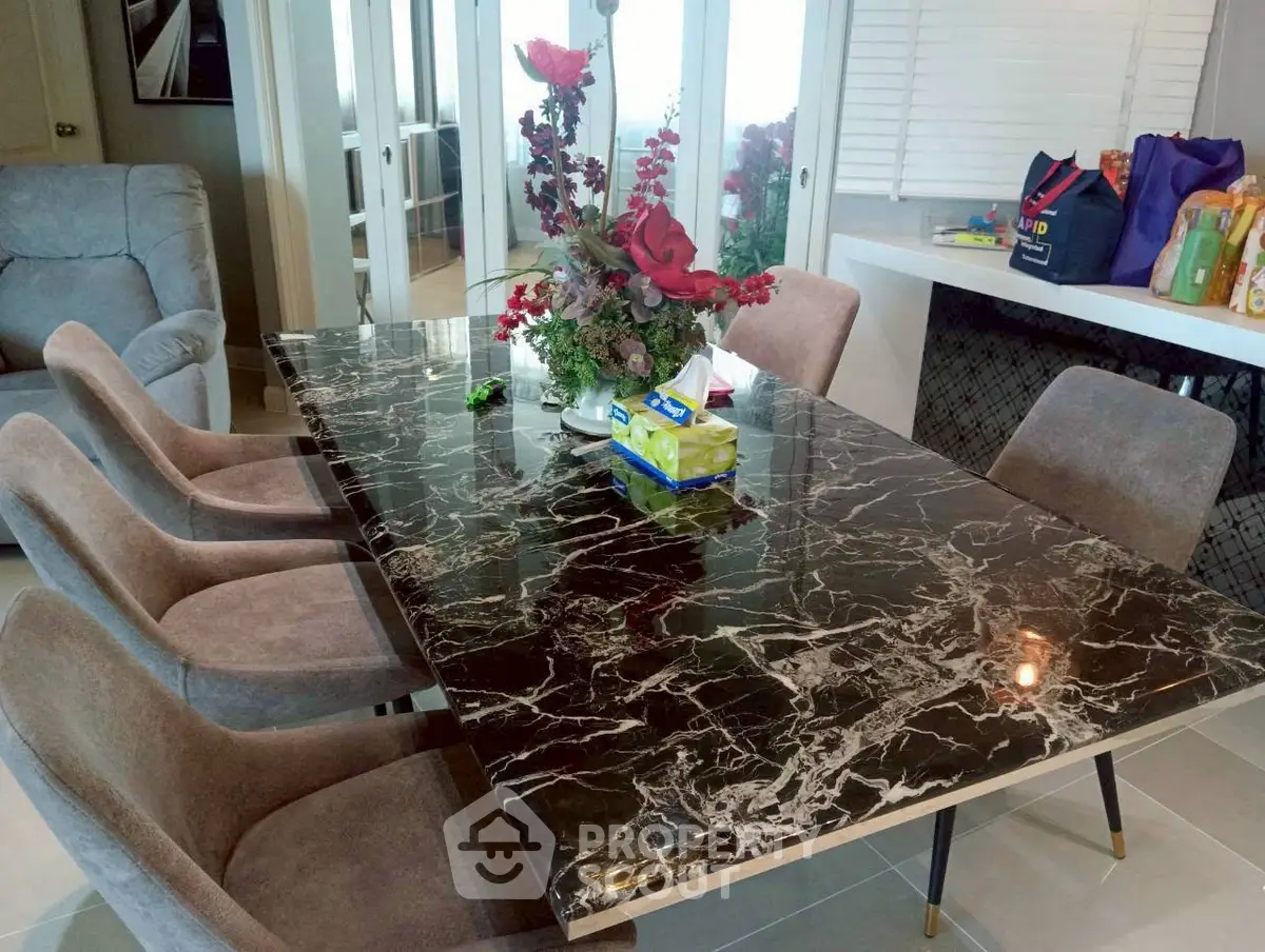 Elegant dining area with marble table and plush chairs in modern home interior.