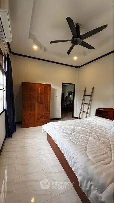 Spacious bedroom with modern ceiling fan and elegant wooden furniture