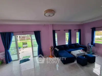 Spacious living room with modern blue sofa and large windows offering natural light.