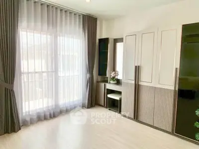 Spacious modern bedroom with large window and elegant curtains