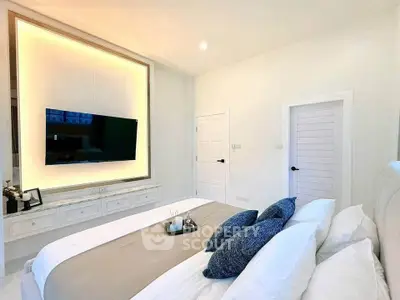 Luxurious bedroom with modern decor and wall-mounted TV, perfect for relaxation.