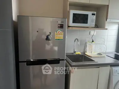 Modern kitchen with stainless steel fridge and microwave in compact layout.