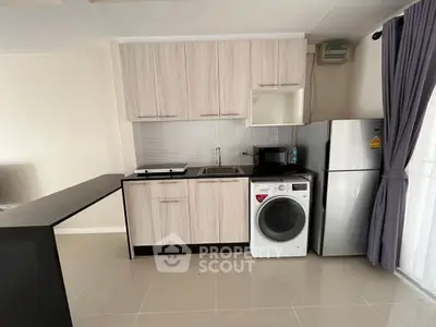 Modern kitchen with sleek cabinetry, washing machine, and fridge in a compact open layout.