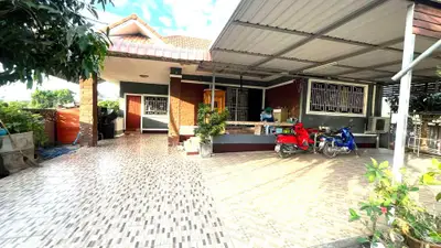 Charming suburban home with spacious tiled driveway and covered parking area.