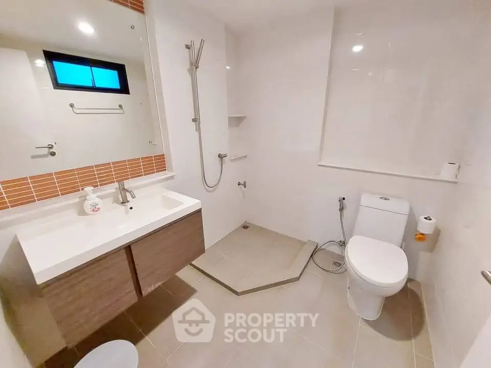 Modern bathroom with sleek fixtures and spacious layout, featuring a walk-in shower and contemporary vanity.