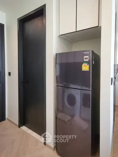Modern kitchen corner with sleek black fridge and wooden flooring