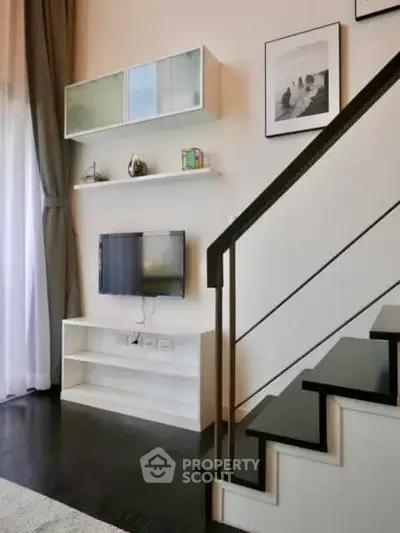 Modern living room with stylish staircase and wall-mounted TV, elegant decor