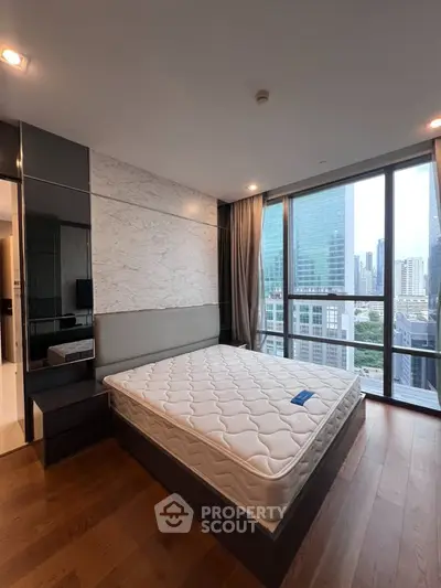 Modern bedroom with large windows offering stunning city views in a high-rise apartment.