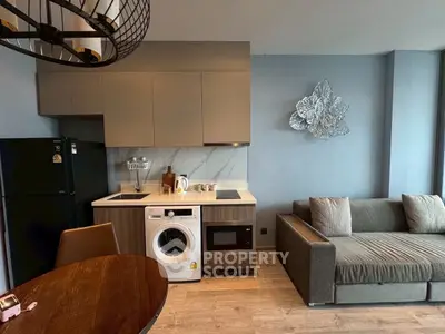 Modern living room with integrated kitchen, featuring a washing machine and stylish decor.