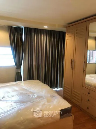 Cozy bedroom with large wardrobe and elegant curtains, perfect for a restful retreat.