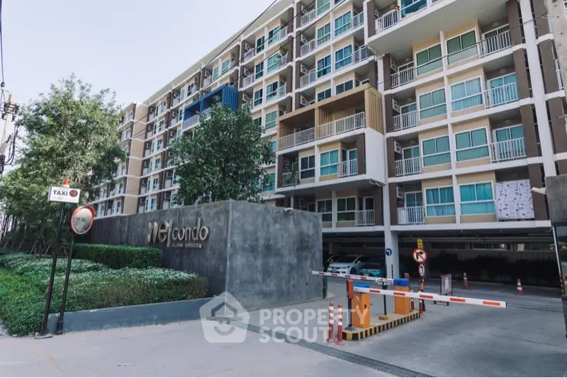 Modern condominium complex entrance showcasing secure access gate, well-maintained facade, and lush greenery, ideal for urban living.