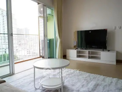 Modern living room with balcony view and sleek TV setup in urban apartment.