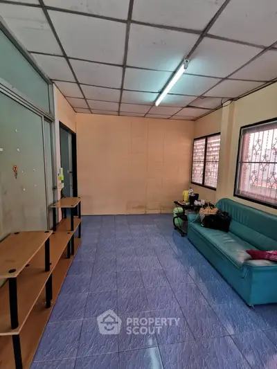 Spacious living room with blue tiled floor and cozy seating area, perfect for relaxation.