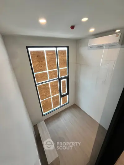 Modern minimalist room with large window and air conditioning, perfect for a cozy study or small bedroom.