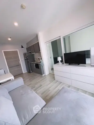 Modern living room with sleek kitchen and cozy seating area in open layout apartment.