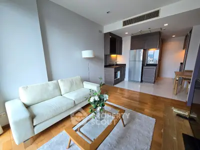 Modern living room with open kitchen, featuring sleek furniture and hardwood floors in a stylish apartment.